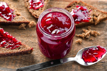 Sticker - Glass jar with delicious homemade plum jam on wooden background