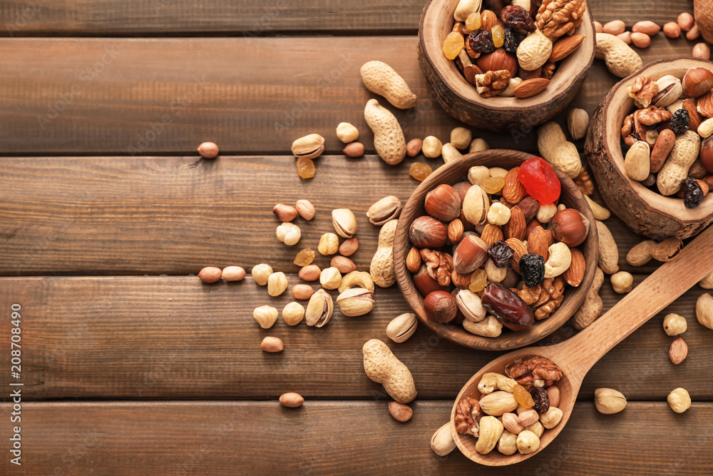 Various tasty nuts with bowls and spoon on wooden table