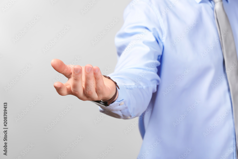 Young businessman holding something on gray background