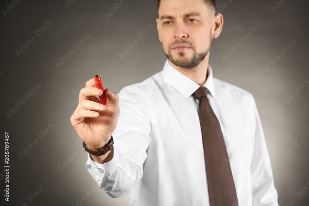 Young businessman writing on virtual screen against color background