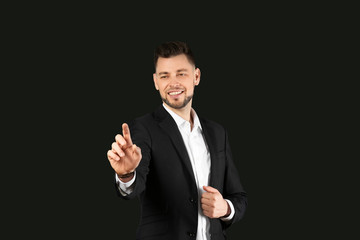 Poster - Young businessman using virtual screen on black background