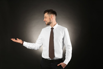 Poster - Young businessman holding something on color background