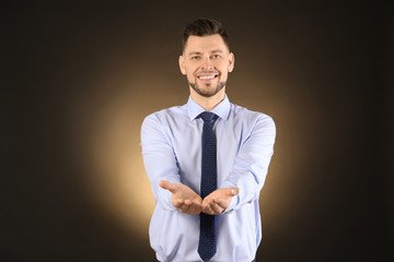 Poster - Young businessman holding something on color background