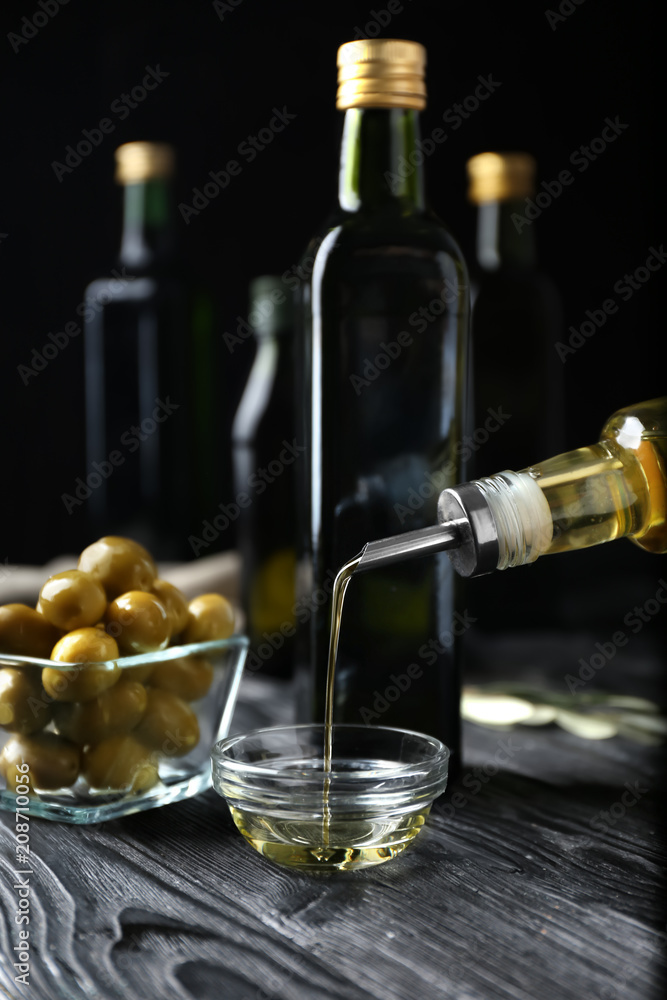 Pouring olive oil into glass bowl on table