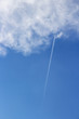 Skyscape with a plane with contrail entering a fluffy cloud