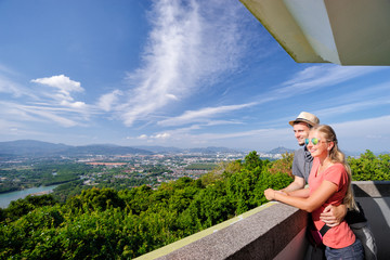 Wall Mural - Tourist attraction. Couple of travelers enjoying sea, city and sky on the view point.