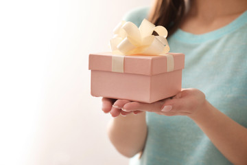 Beautiful young woman with gift box on color background, closeup