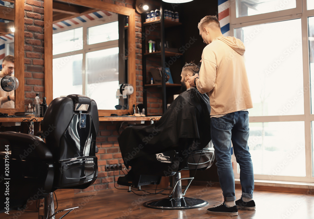 Professional barber working with client in hairdressing salon