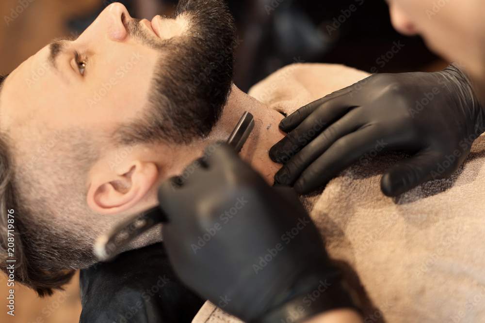 Professional barber working with client in hairdressing salon