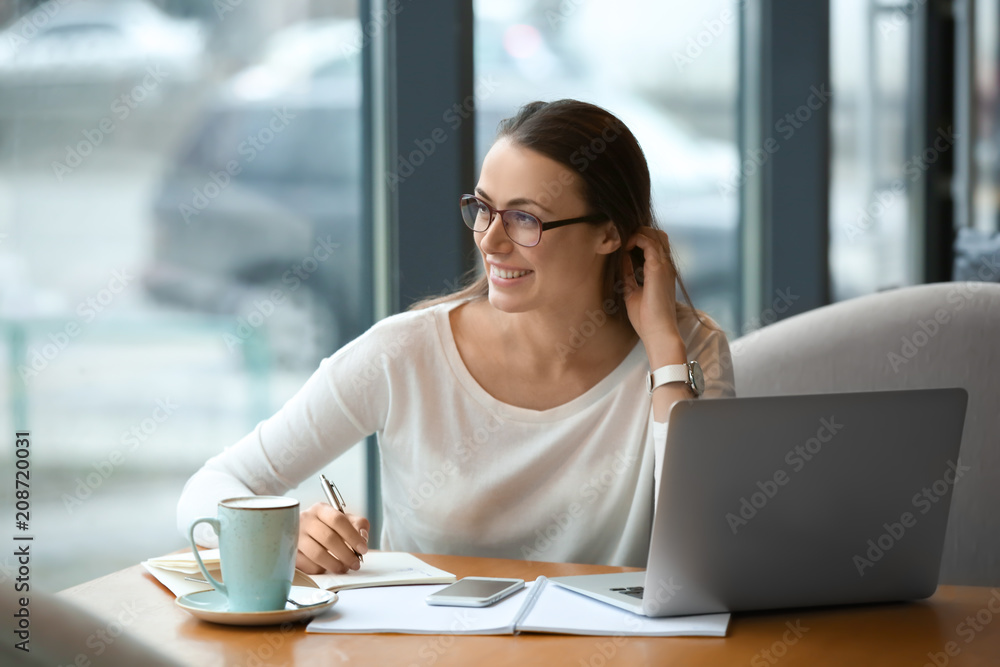 Young freelancer with laptop working in cafe