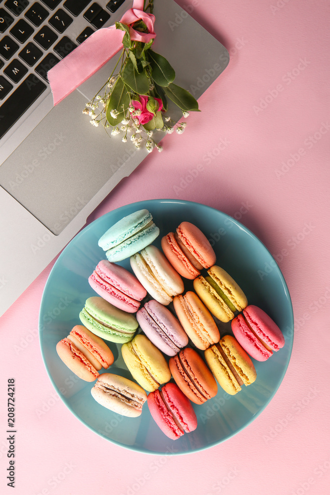 Flat lay composition with macarons, laptop and flowers on color background