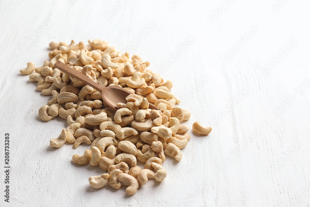 Tasty cashew nuts on white wooden background
