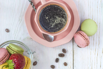 Wall Mural - Cup of coffee and french macaroons with strawberry on white wooden background top view.