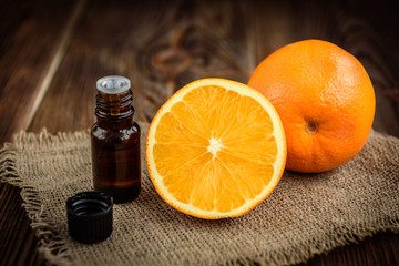 Bottle of orange essential oil on dark wooden background. Spa ingredients.