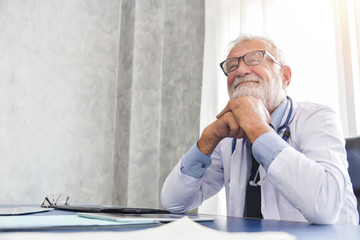 Wall Mural - Senior male Doctor is smiling in a medical room.