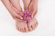 © LIGHTFIELD STUDIOS - partial view of barefoot woman with flowers on pedicure procedure in beauty salon