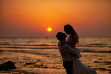 Wall Mural - Bride and groom, newlyweds, honeymoon on the beach sunset sun