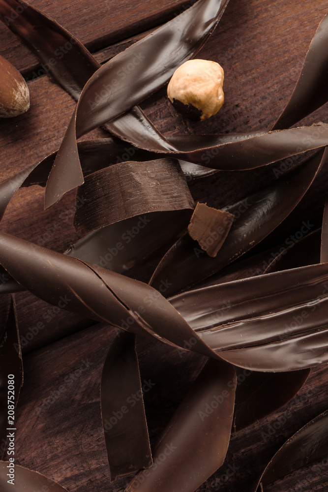 Delicious chocolate, shavings and nut on table, closeup