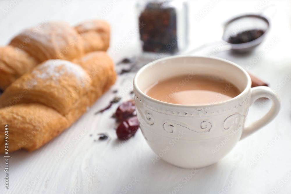 Cup of aromatic tea with milk on wooden table
