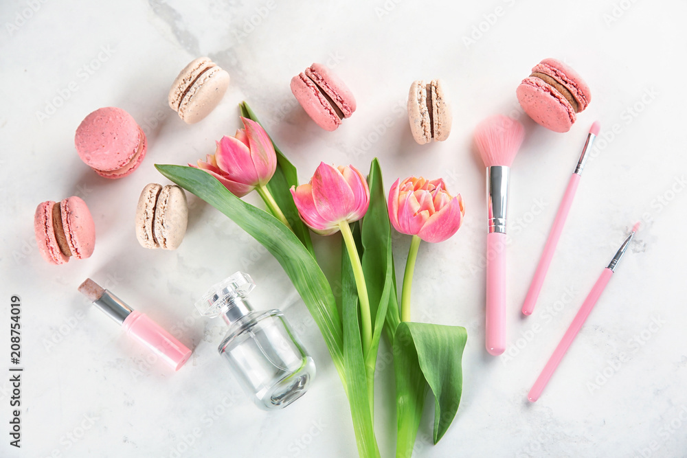 Flat lay composition with tasty macarons, tulips and beauty accessories on light background