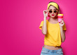 © Masson - Girl in sunglasses and yellow t-shirt holding a red cup of coffee on pink background