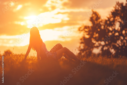 Fotografia Girl enjoying in the meadow at golden sunset time.