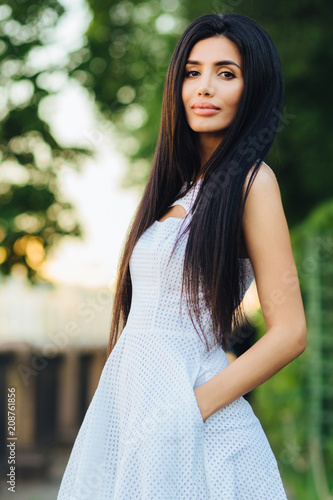 Slim Healthy Female Model Wears White Dress Keeps Hands In Pocket