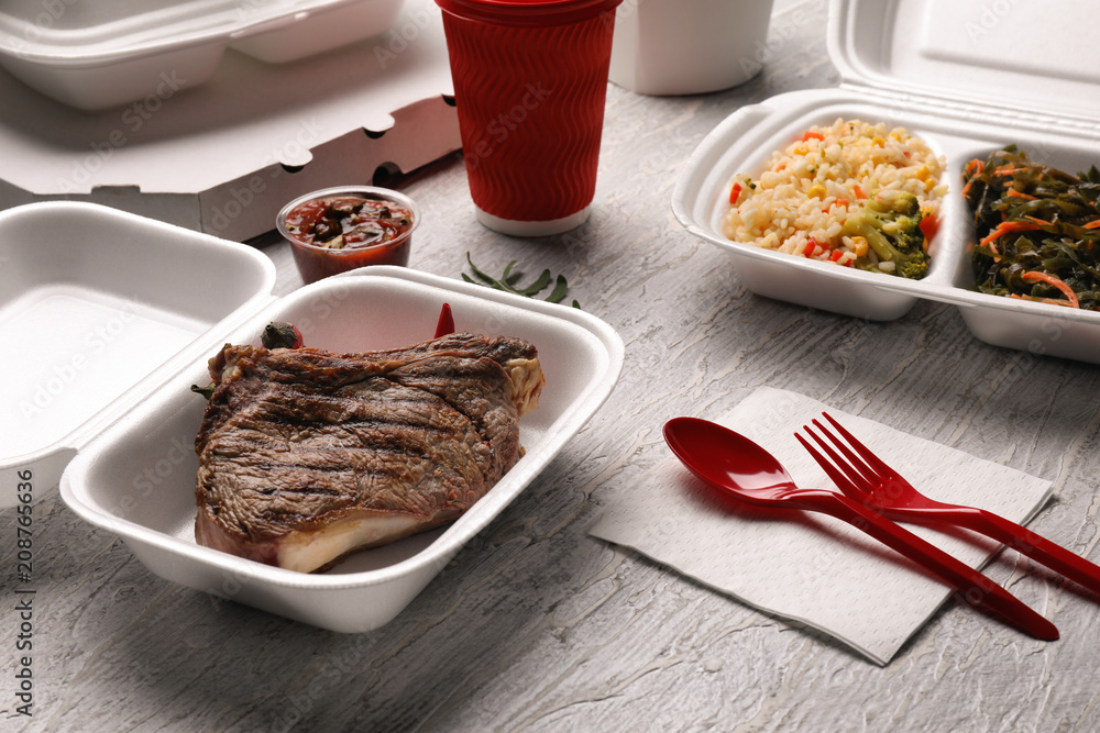 Container with delicious food on wooden table. Delivery service