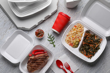 Different containers with delicious food on wooden table. Delivery service