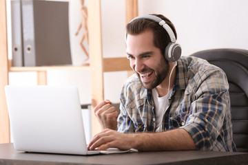 Wall Mural - Young man playing video games on laptop at home