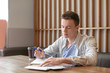 © Pixel-Shot - Young man writing letter at table in cafe. Mail delivery