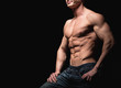 © sergiophoto - Fitness concept. Muscular and fit torso of young man having perfect abs, bicep and chest. Male hunk with athletic body on black background