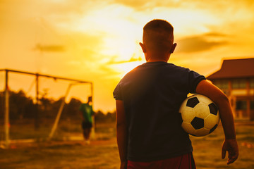 Wall Mural - An action sport picture of a group of kid playing soccer football for exercise in before the sunset. Picture with copy space for world cup concept.