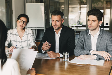 Poster - Business, career and placement concept - three executive directors or head managers sitting at table in office, and interviewing woman for job in company