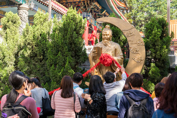 Yue Lao Statue with group tourist at Wong Tai Sin Temple in Hong Kong, China. Wong Tai Sin or Huang Daxian is a Chinese Taoist deity popular in Hong Kong.