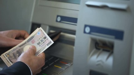 Wall Mural - Man counting Japanese Yen withdrawn from ATM, putting cash in wallet, tourism