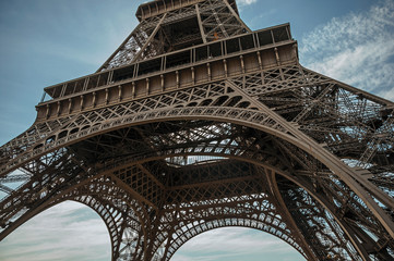 Wall Mural - Bottom view of Eiffel Tower made in iron and Art Nouveau style, with sunny blue sky in Paris. Known as the “City of Light”, is one of the most impressive world’s cultural center. Northern France.