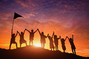 Silhouettes of children standing in a row holding hands.