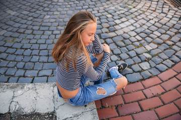 Wall Mural - young teenage poses to photographer. blonde girl in jeans and blouse