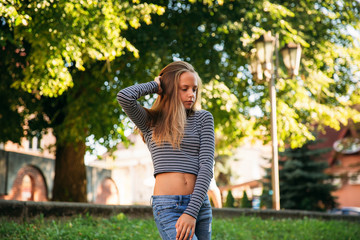 Wall Mural - blonde teenage girl in striped blouse on the backgrountd of green tree