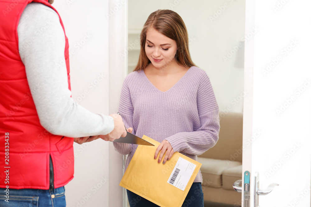 Woman signing for parcel delivery at doorway
