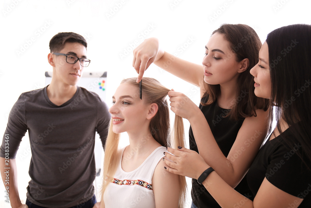 Professional hairdresser and trainees working with client in salon. Apprenticeship concept