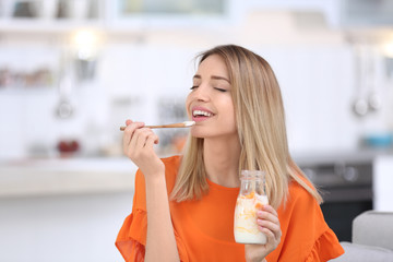 Poster - Young attractive woman eating tasty yogurt in kitchen