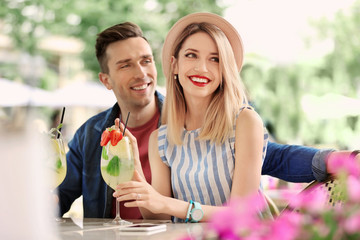 Poster - Young couple with glasses of tasty lemonade in open-air cafe