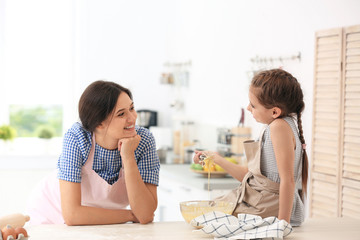 Canvas Print - Mother and her daughter making dough at table in kitchen