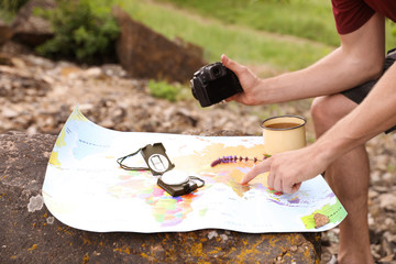 Poster - Man with camera exploring map in wilderness. Camping season