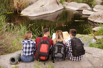 Poster - Young people exploring map in wilderness. Camping season