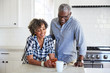 © trinettereed/Stocksy - African American Senior Couple looking at cell phone in the kitchen together