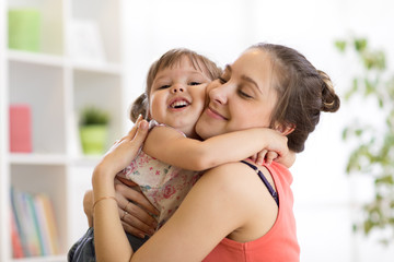 Wall Mural - love and family concept - happy mother and child daughter hugging at home