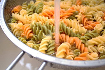 Fusilli (Fuso) - classic Italian pasta in the form of a spiral of durum wheat. Ingredient for cooking a traditional Italian dish. Cooking process. Soft focus, close-up. A place to copy.